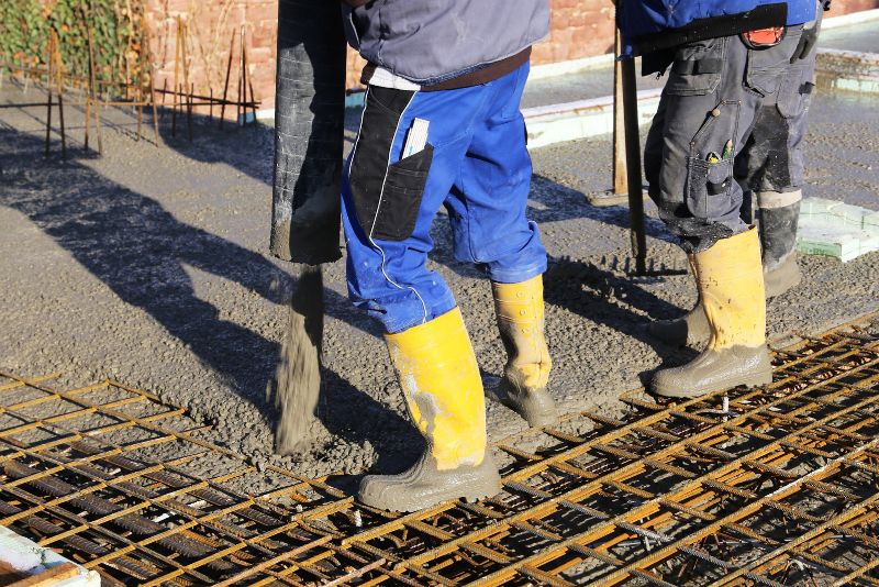 Concrete crew pouring and levelling a fresh concrete slab