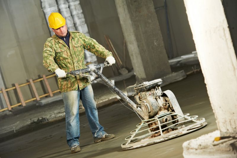 Worker operating a power trowel to finish a concrete floor