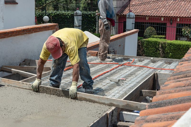 two concrete workers levelling a concrete slab