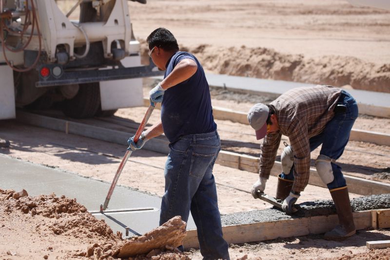 Workers finishing a freshly poured concrete pathway
