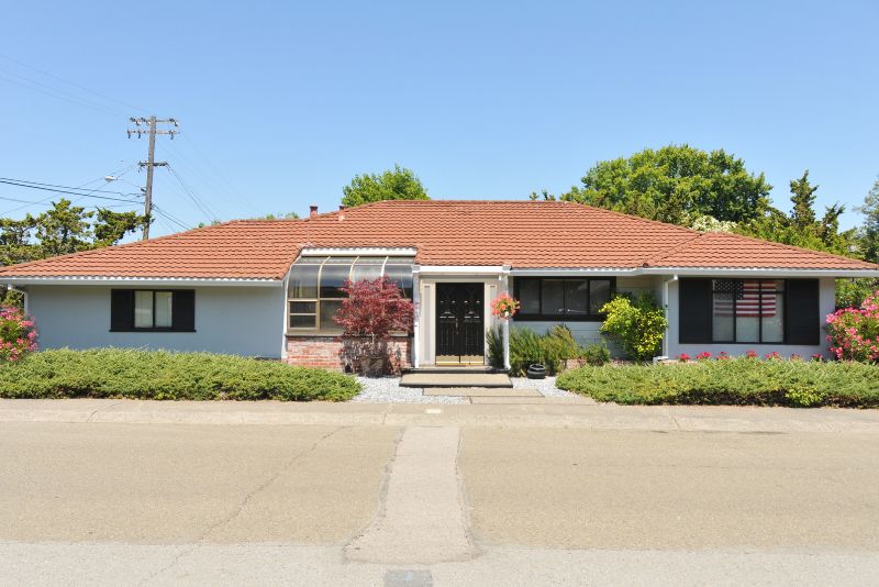 Single-storey home exterior with a paved street and established gardens
