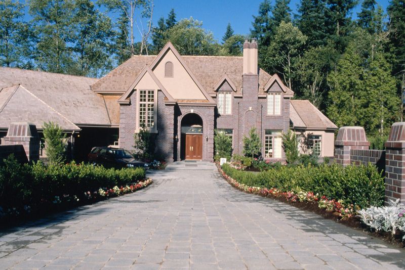 Paved stone driveway leading to a large brick home
