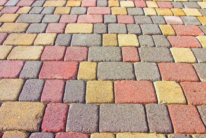 Multi-coloured brick paver surface laid in a herringbone pattern