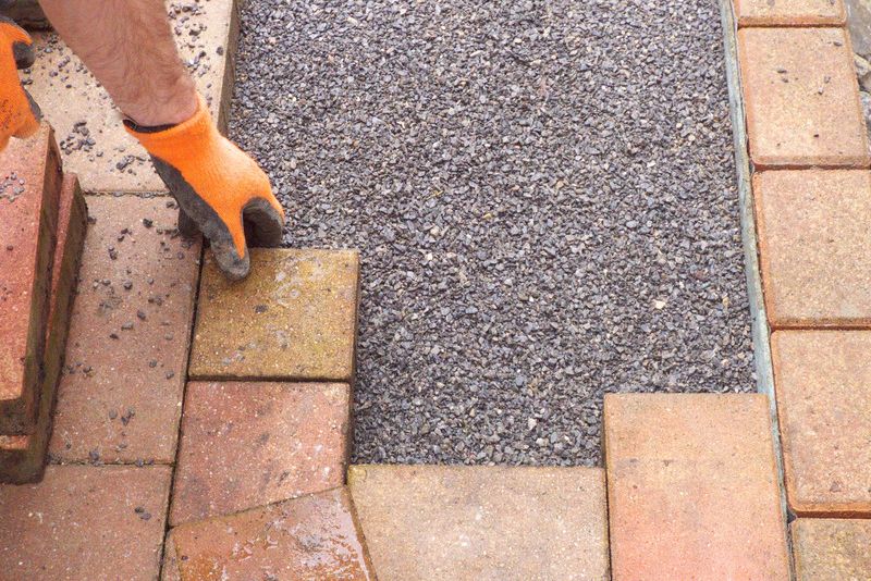Contractor laying concrete pavers for a new pathway