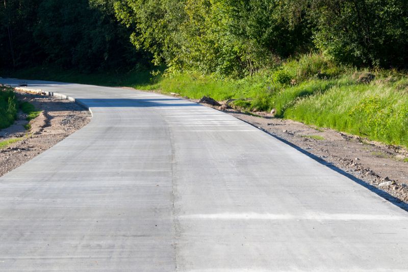 Newly poured concrete road through a wooded area