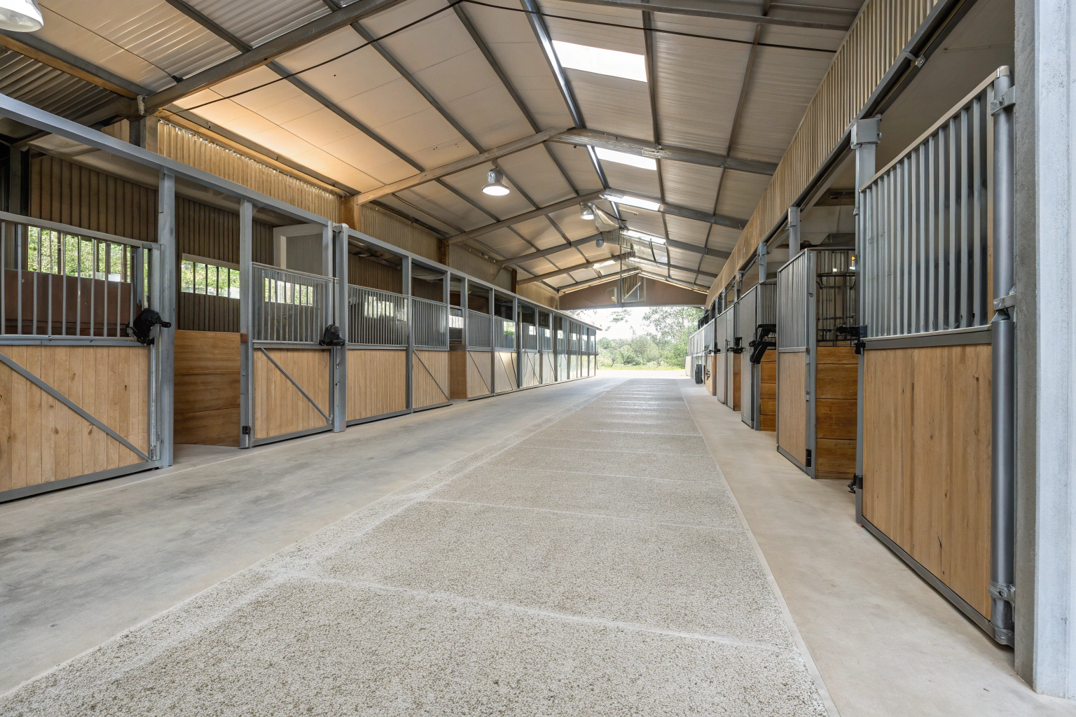 Interior view of modern horse stable with textured concrete floor
