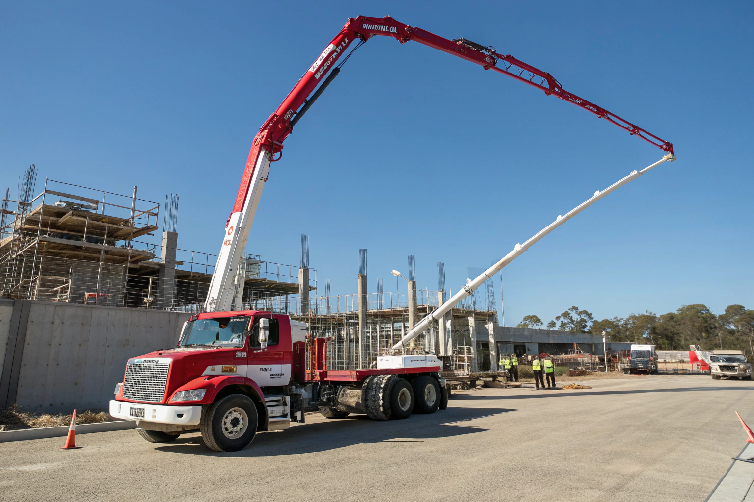 Large red and white concrete boom pump truck positioned on site